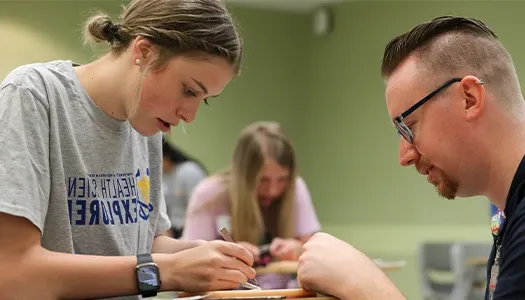 an instructor helps a student work on a project at her desk