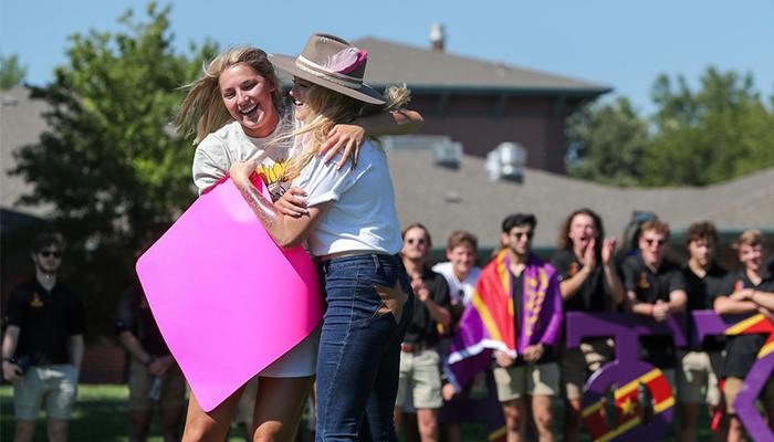 two students hug during bid day